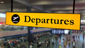 A Flight departures sign against the background of an airport concourse